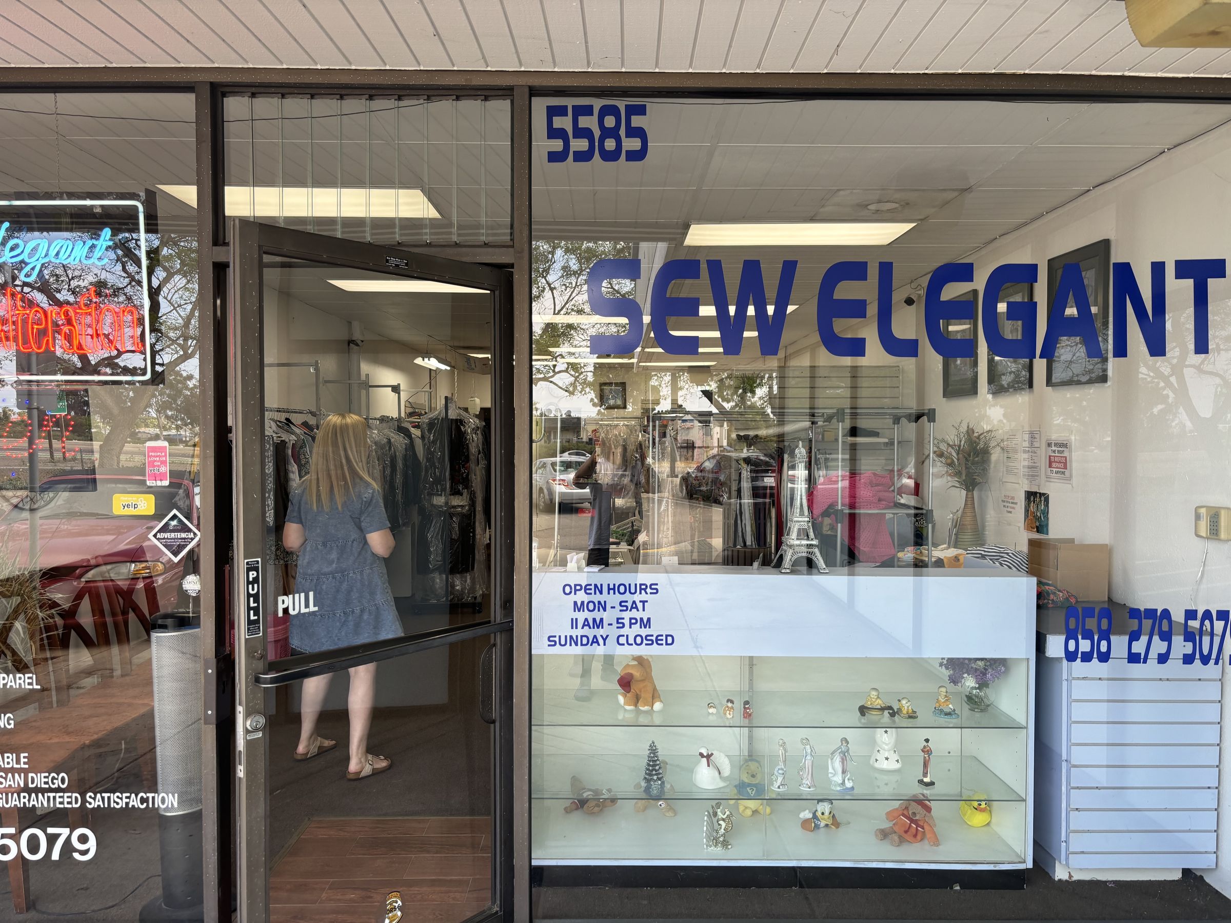 Front window at 5585 with the Sew Elegant lettering and posted hours